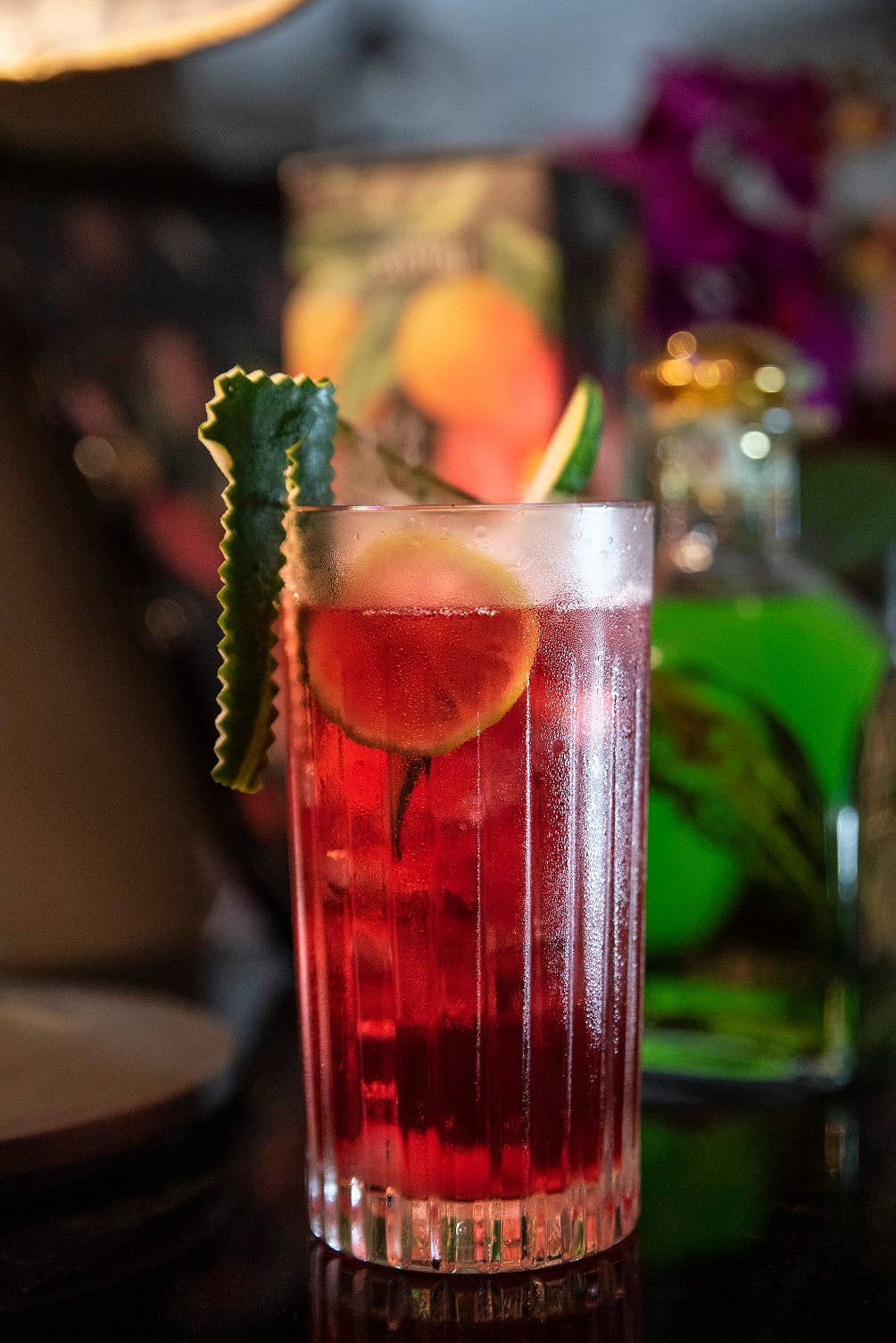 Longdrinkglas i kristall med en röd cocktail i.