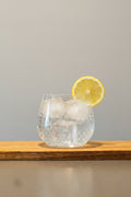 Dryckesglas i kristall med bubbelvatten i, toppad med en citronskiva.