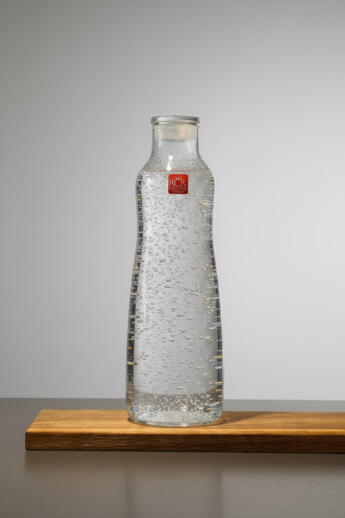 Glasflaska i kristall fylld med mineralvatten. 