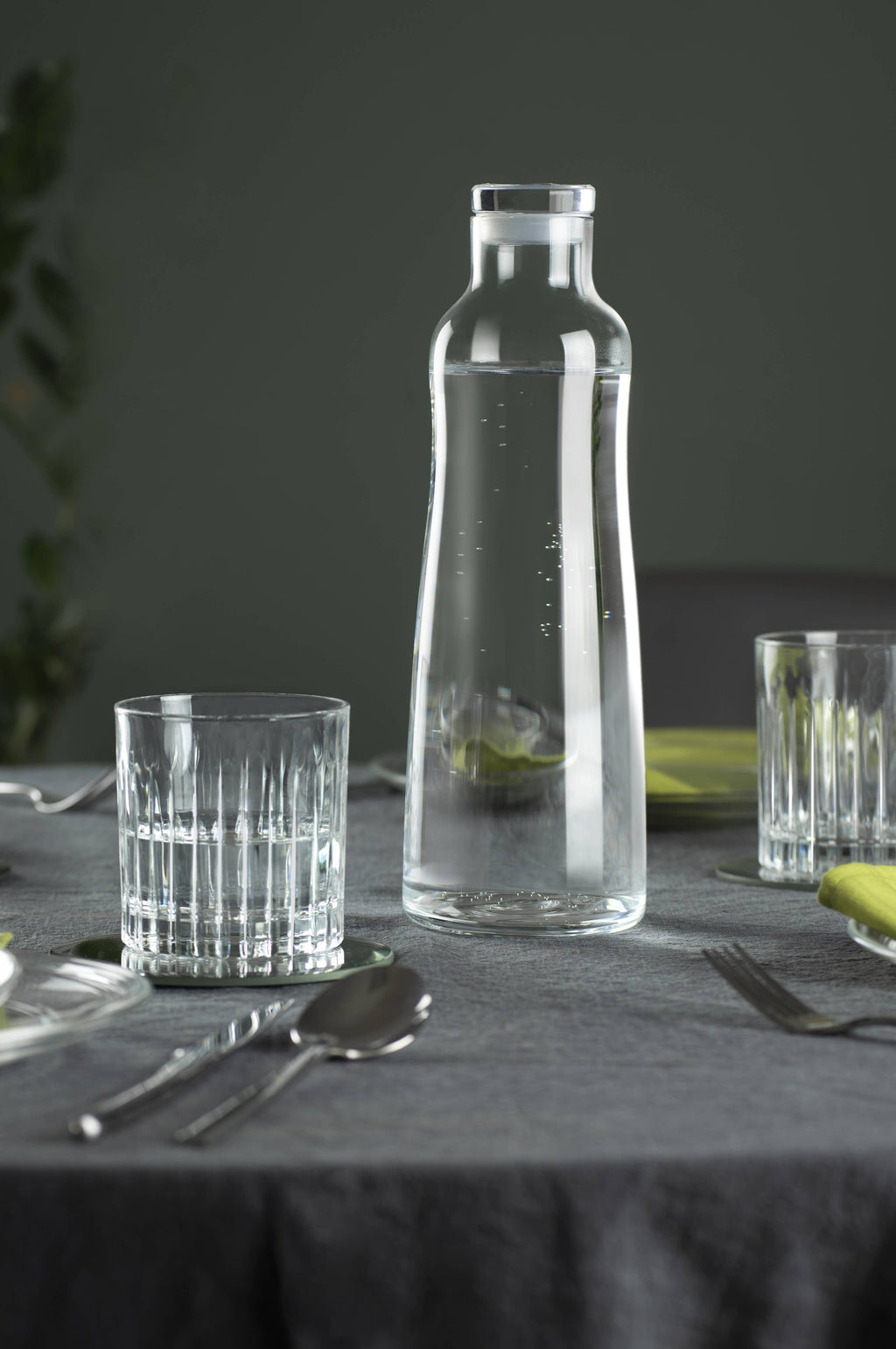 Glasflaska i kristall på ett elegant dukat bord med vatten i.